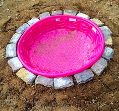 a pink frisbee sitting on top of a pile of rocks in the dirt