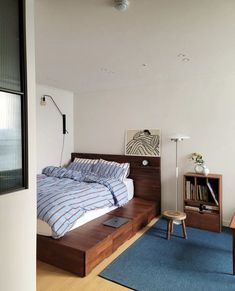 a bedroom with a bed, night stand and desk in front of a large window