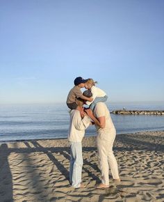 two people are standing on the beach with their arms around each other as they hug