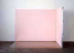 an open pink box sitting on top of a wooden floor next to a white wall