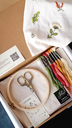 an open box containing scissors, thread and other crafting supplies on top of a table