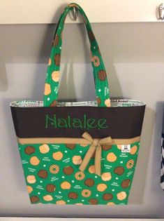 a green and brown bag hanging from a hook on a wall with the name natalie written on it