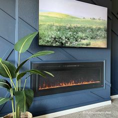 a blue wall with a painting on it and a fire place in front of the fireplace