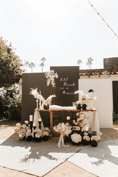 the dessert table is set up outside with white flowers and candles on it, along with black and white decor