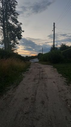 a dirt road with trees and power lines in the background