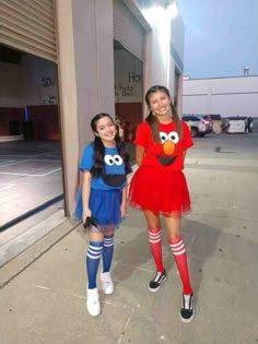 two girls in costumes standing next to each other on the sidewalk, one wearing an angry bird costume