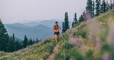 a man running down a trail in the mountains