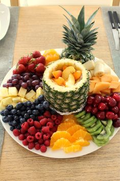 a white plate topped with lots of fruits and veggies next to a pineapple