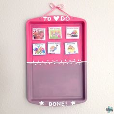 a pink tray with pictures on it hanging from the wall next to a white wall