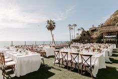 tables and chairs set up on the beach for an outdoor wedding reception with palm trees in the background