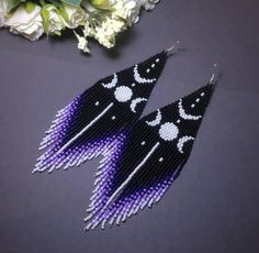 black and purple beaded earrings with white beads on them, next to some flowers