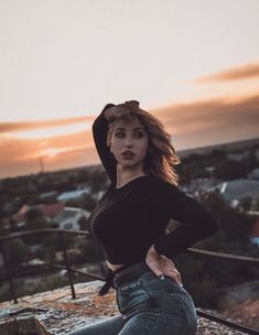 a woman posing on top of a building with her hands on her hips and looking at the camera