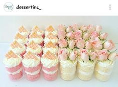 there are many pink and white cakes in vases on the table with flowers inside