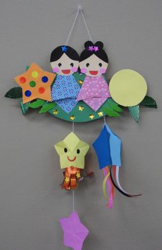 an origami mobile with two girls hanging from it