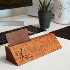 a wooden business card holder sitting on top of a desk next to a computer keyboard