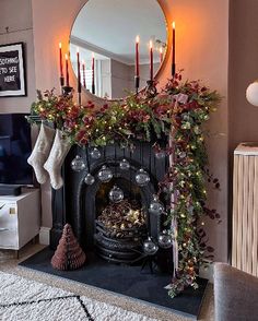 a living room filled with furniture and a fire place covered in christmas decorations next to a mirror