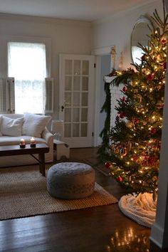 a living room with a christmas tree in the corner and a dog bed on the floor