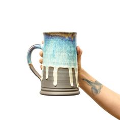 a hand holding a coffee mug with white and blue drips