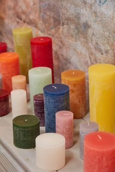 many different colored candles sitting on top of a table