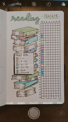 a notebook with some books on top of it and the words reading tracker written in green