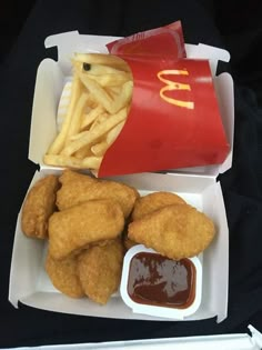 chicken nuggets, fries and ketchup in a takeout box with french fries