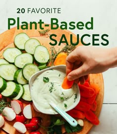 a person is dipping sauce into vegetables on a cutting board