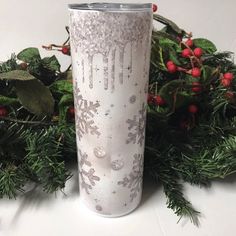 a white frosted cup sitting on top of a table next to christmas greenery