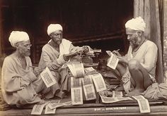 three men sitting on the ground with newspapers in their hands and papers scattered around them