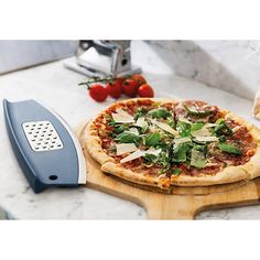 a pizza sitting on top of a wooden cutting board next to a knife and tomatoes