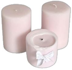 three pink candles with a white bow on the top and one candle in the middle