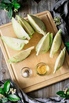 sliced avocados on a cutting board with olive oil and leaves around them,