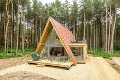 a small wooden cabin in the middle of a forest with tables and chairs on it