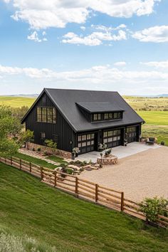 a large black barn style home with a covered patio and fenced in yard area