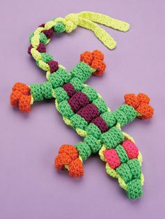 a crocheted lizard on a purple surface