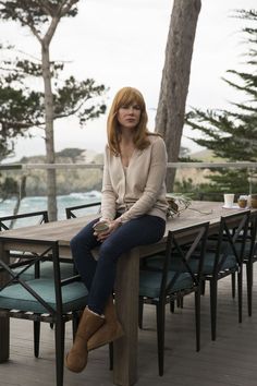 a woman sitting on top of a wooden table