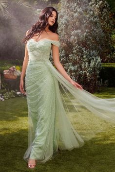 a beautiful woman in a green dress posing for the camera with her long veil flowing over her shoulder