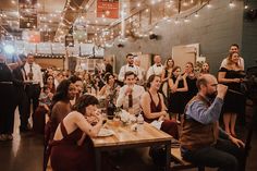 a group of people sitting around a wooden table in a room with lights on the ceiling