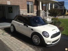 a small white car is parked in front of a house with a hose attached to it