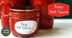 four jars filled with homemade hot sauce sitting on a white counter top next to a red sign that says easy hot sauce