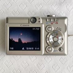 a silver camera sitting on top of a white blanket