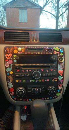 the dashboard of a car decorated with stickers and hearts is shown in front of a house