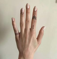 a woman's hand with two small tattoos on her left thumb and one finger