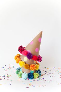 a party hat with pom - poms on it is surrounded by confetti and sprinkles