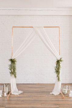 the wedding arch is decorated with greenery and white draping, along with candles