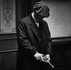 a man in a suit and tie holding a pair of scissors while standing next to a building