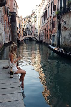 a woman sitting on a bench next to a canal