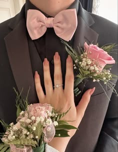 a man in a tuxedo with two flowers and a ring on his finger