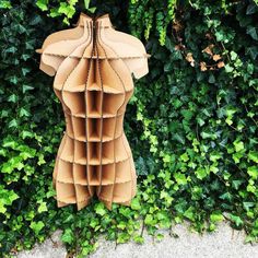 a paper sculpture made to look like a woman's torso in front of green foliage