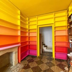 an empty room with orange, pink and yellow shelves on either side of the door