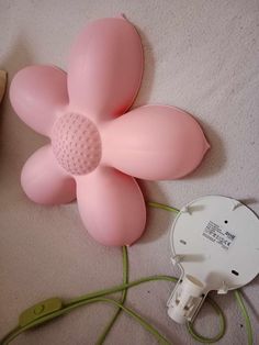 a pink flower shaped object sitting on top of a white floor next to a green cord